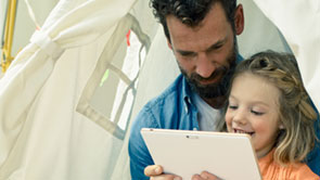 Vater und Tochter schauen zusammen in ein Tablet.