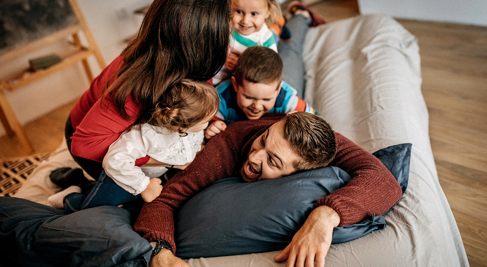 Bild: Vater liegt auf dem Sofa, Mutter und Kinder legen sich auf ihn.