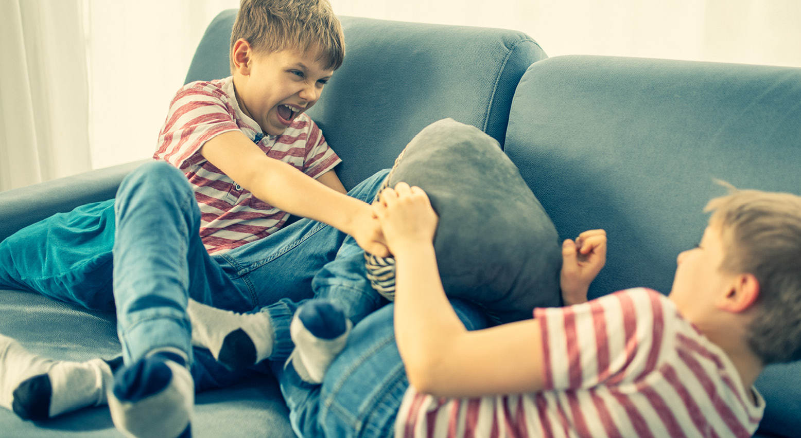 Zwei Jungs balgen sich auf der Couch.  